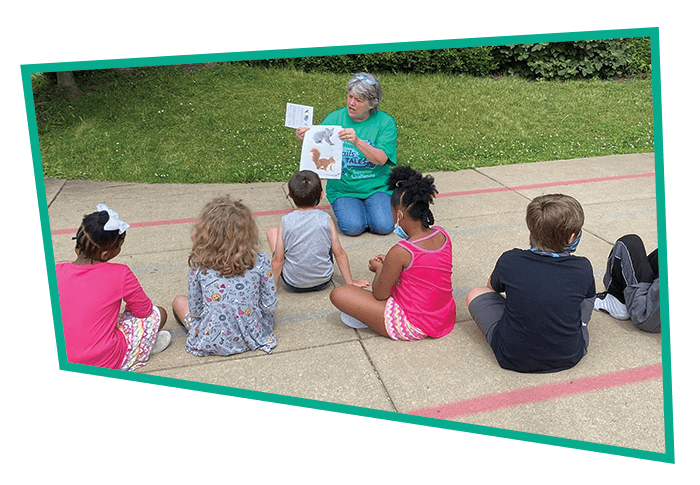IMAGE-DONATE-readingtochildren A friendly staff member reads to a group of children outside